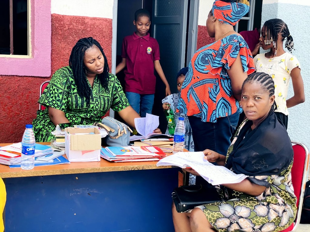 Parents and staff at the admission table with forms and exercise books